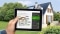 Tablet with modernisation calculator; in the background: detached houses